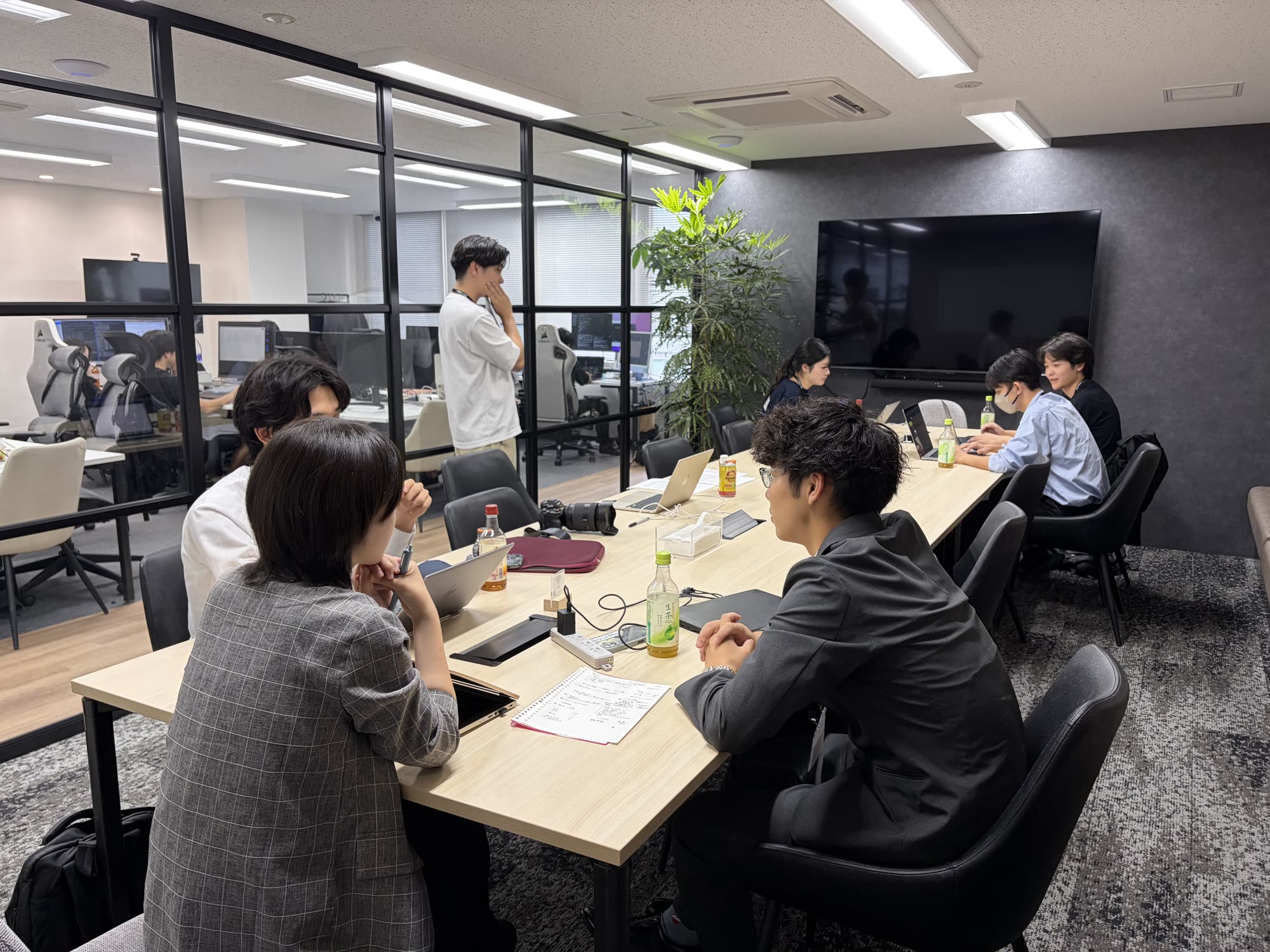第1回大会でチームがテーブルを囲み、社員と議論している様子